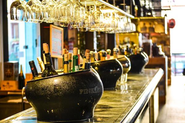 Liquor bottles and wine glasses on a warmly-lit bar counter